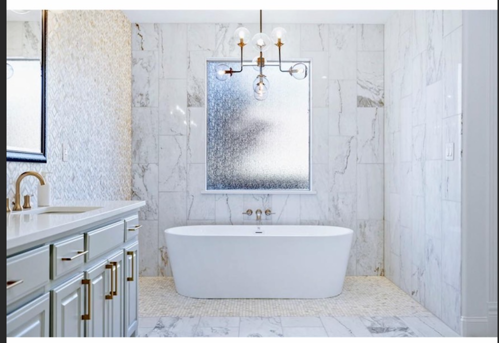 Primary bath soaking tub with marble surround and chandelier
